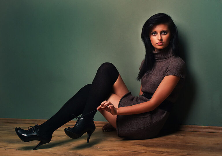 Modelka z czarnymi włosami pozująca do zdjęcia siedzi na podłodze.